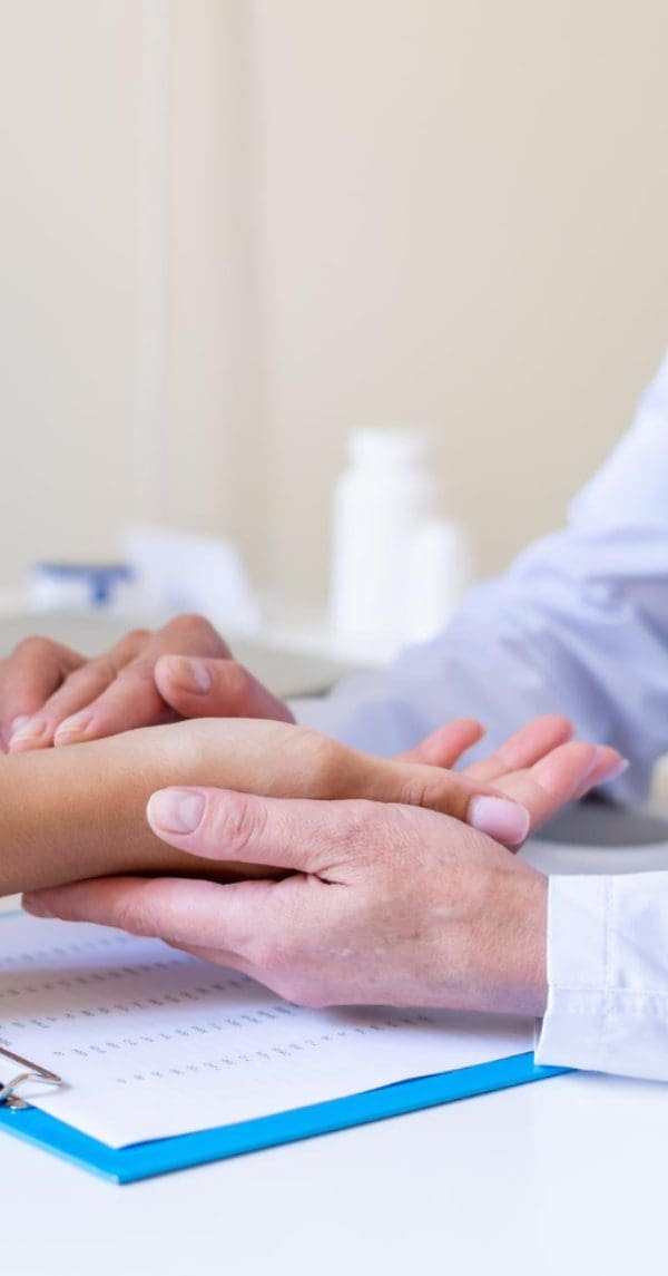 Médico segurando a mão de paciente durante atendimento